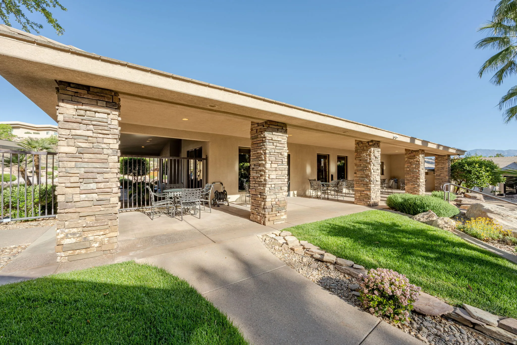 Rear view of house featuring stucco siding, outdoor dining space, a patio, and stone siding