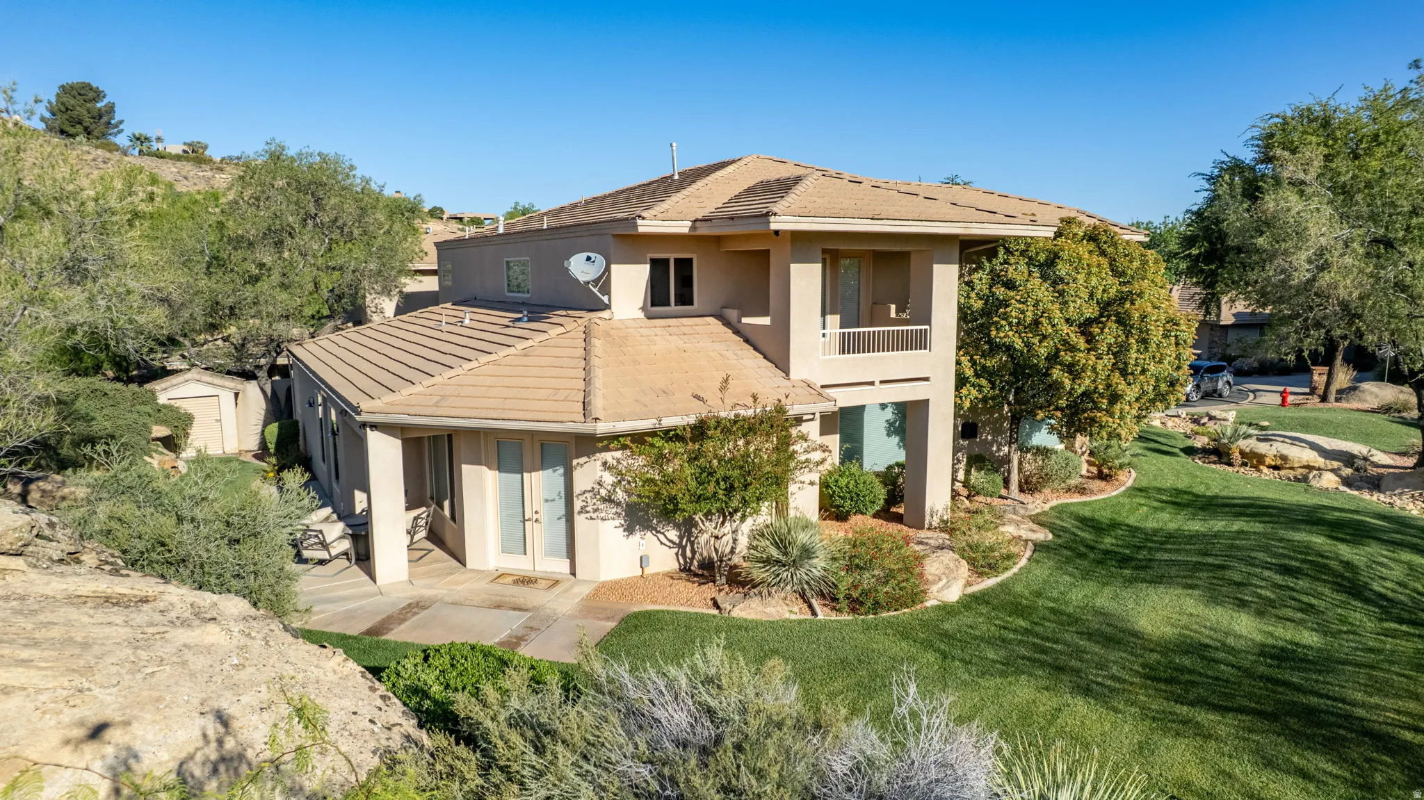 Rear view of house with stucco siding, a tile roof, french doors, and a balcony