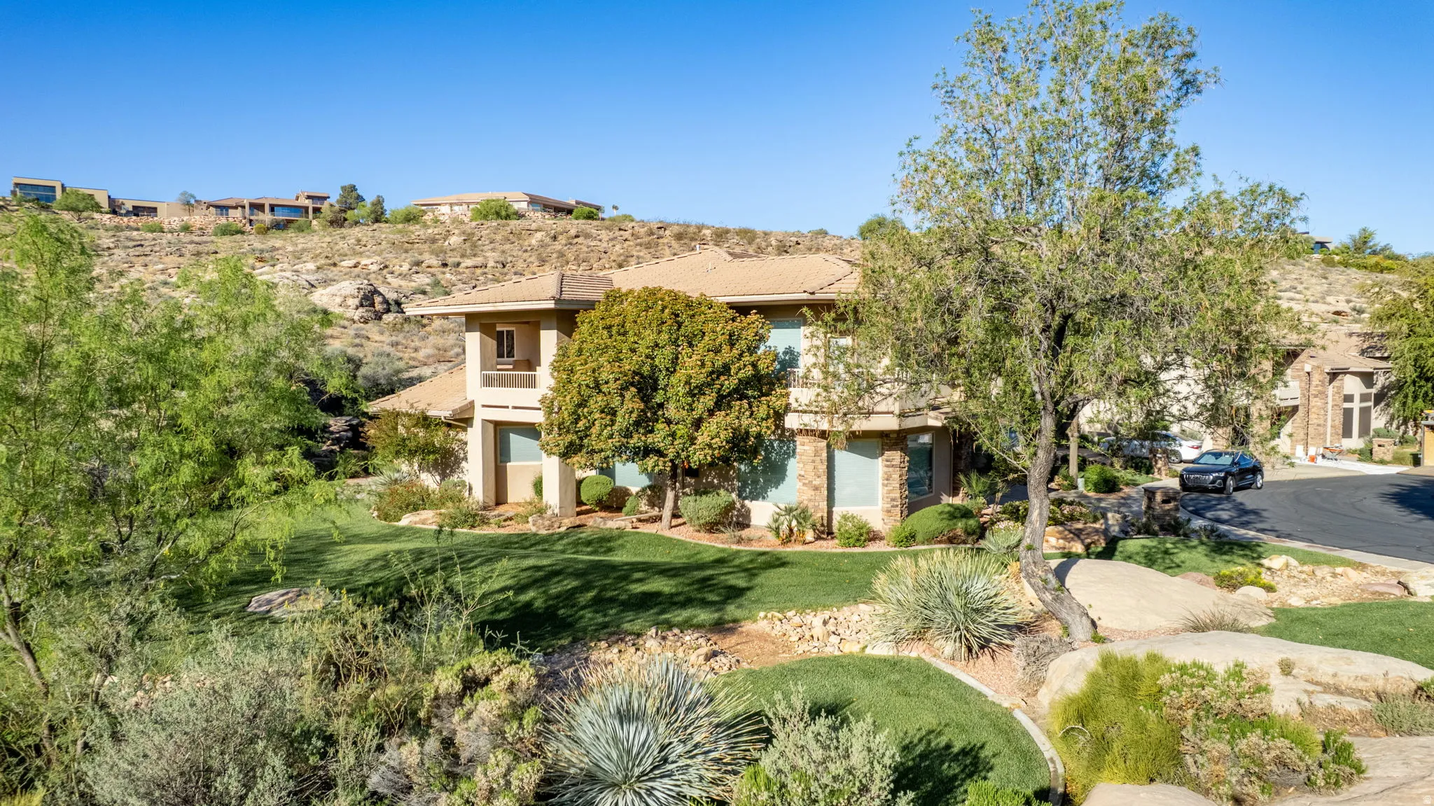 View of property hidden behind natural elements with a front lawn and stucco siding