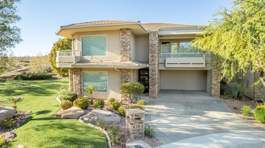 View of front of house featuring a balcony, an attached garage, a front lawn, and stucco siding