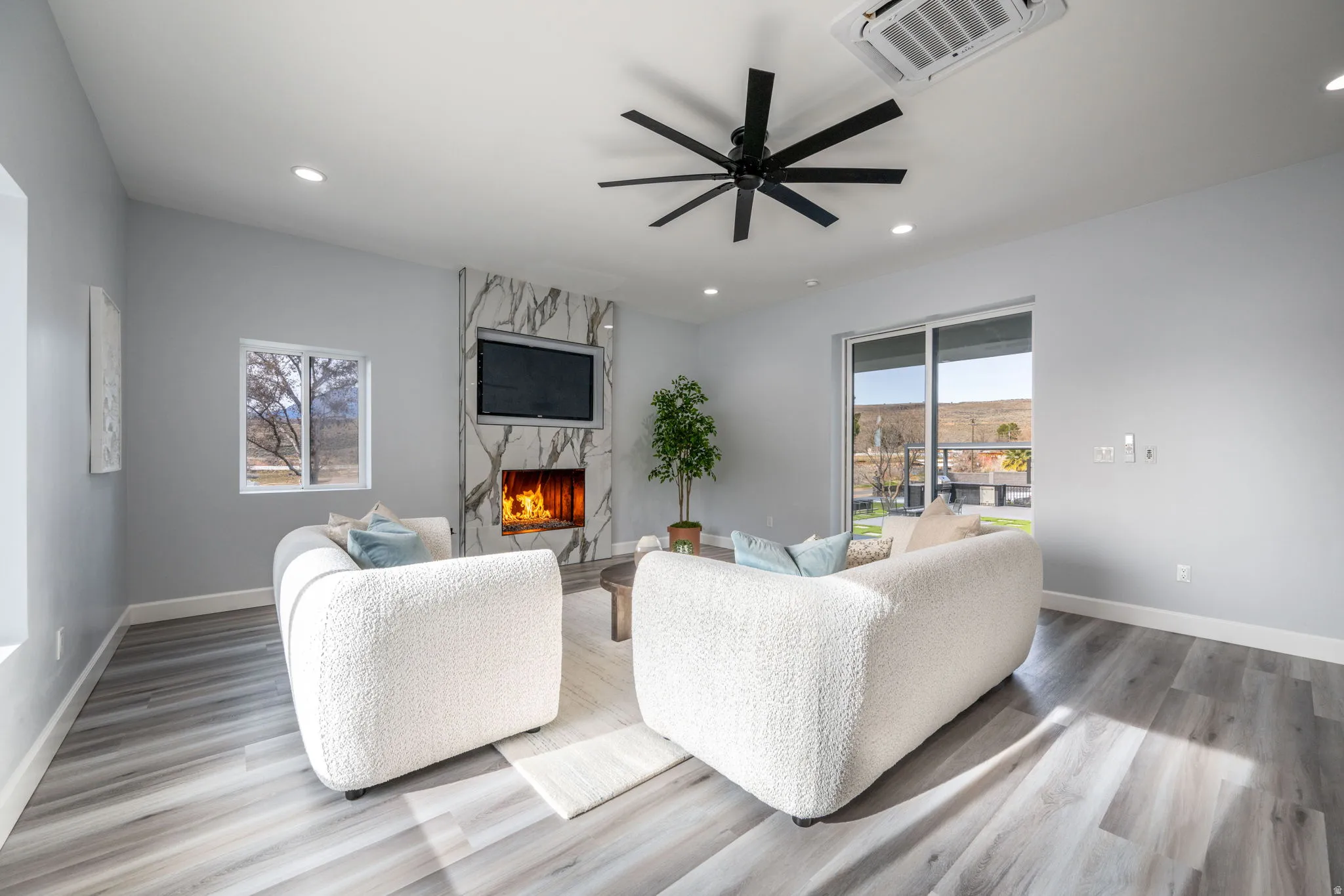 Living area featuring light wood-style flooring, a ceiling fan, a high end fireplace, and recessed lighting