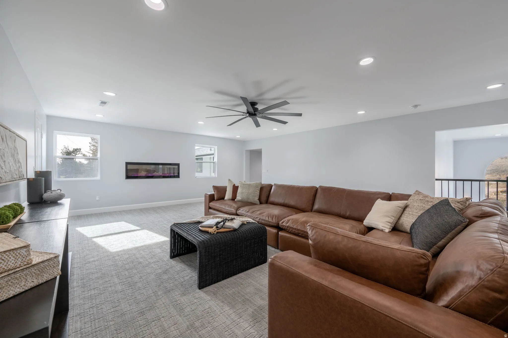 Living area with carpet, ceiling fan, recessed lighting, and a glass covered fireplace