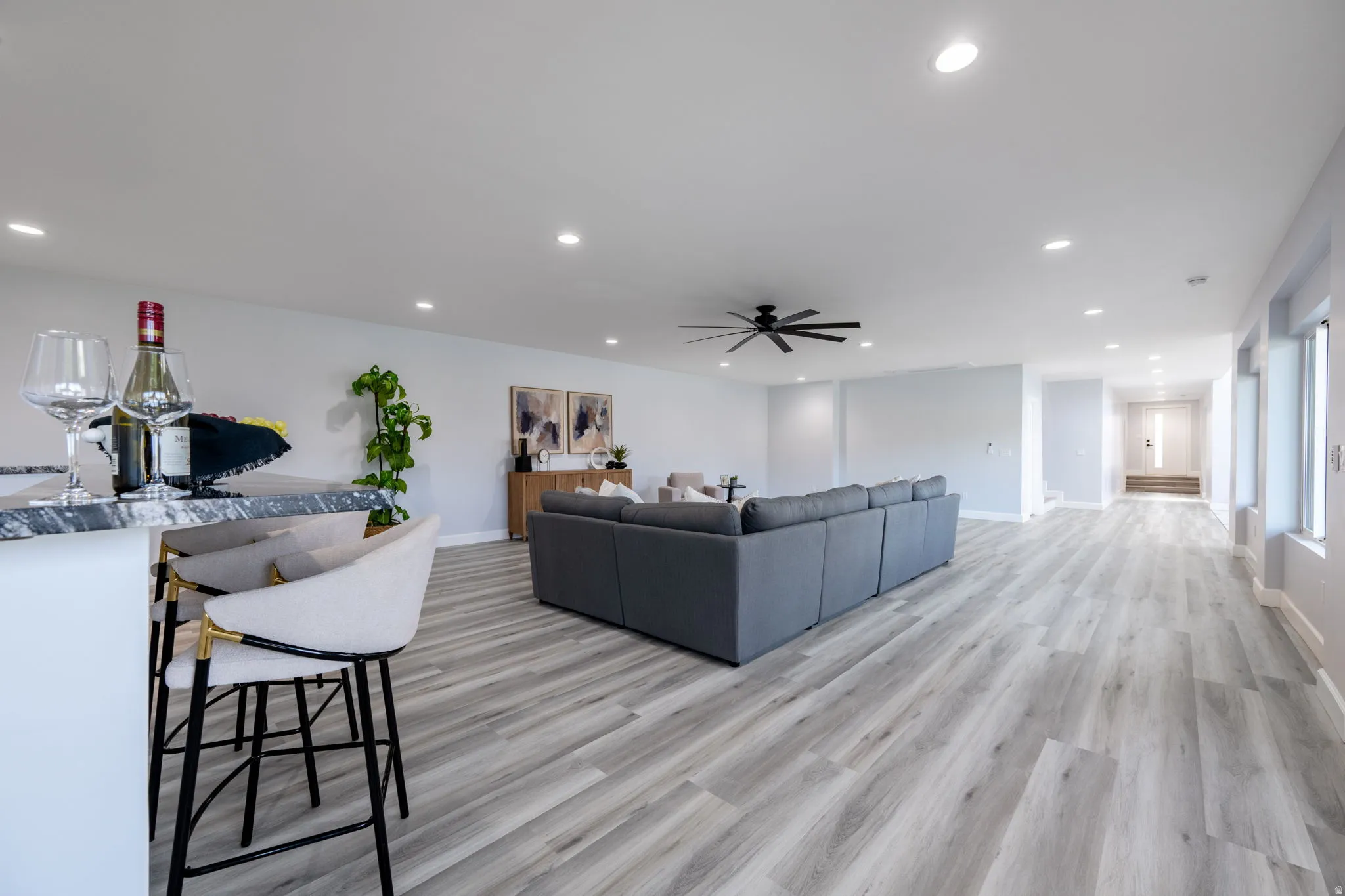 Living area with light wood-style flooring, a ceiling fan, and recessed lighting