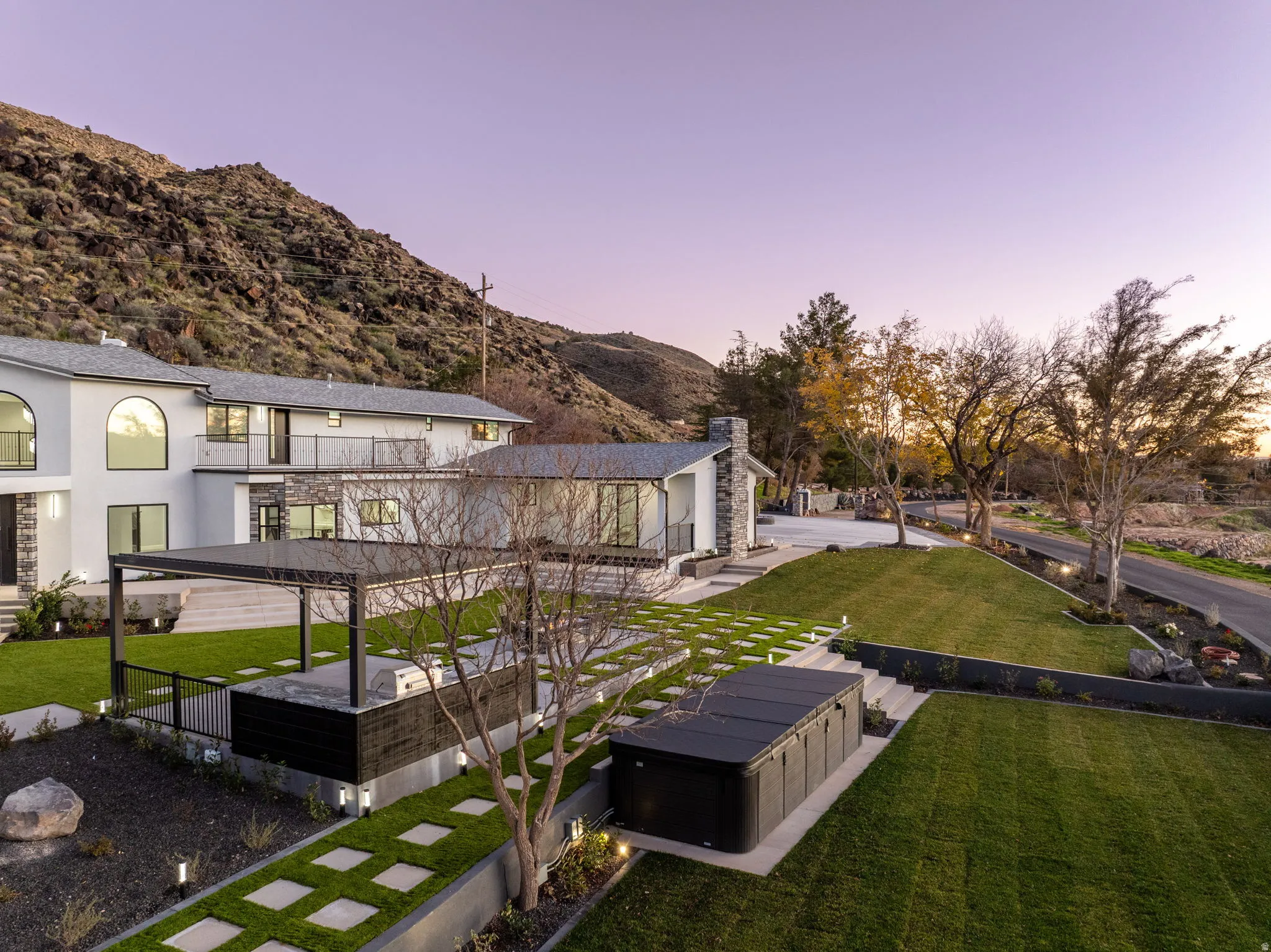 Rear view of property featuring a lawn, a patio area, stucco siding, and a mountain view