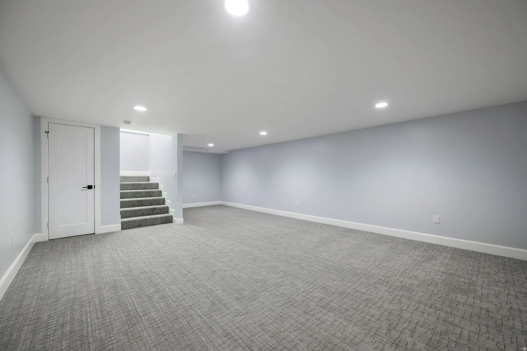 Finished basement with light colored carpet and recessed lighting