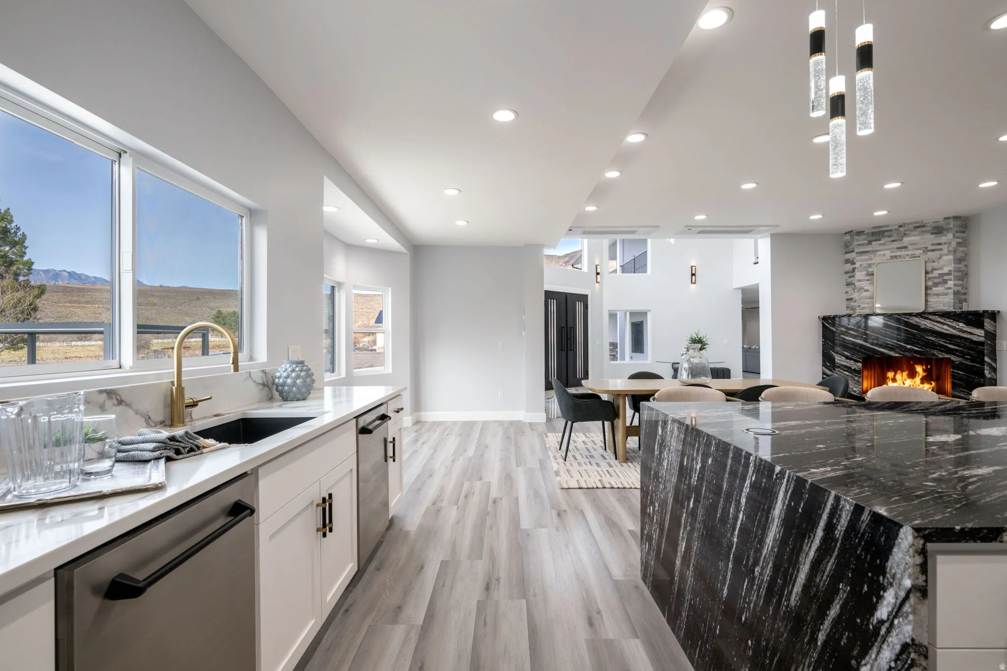 Kitchen with dark stone countertops, dishwasher, open floor plan, and a large fireplace