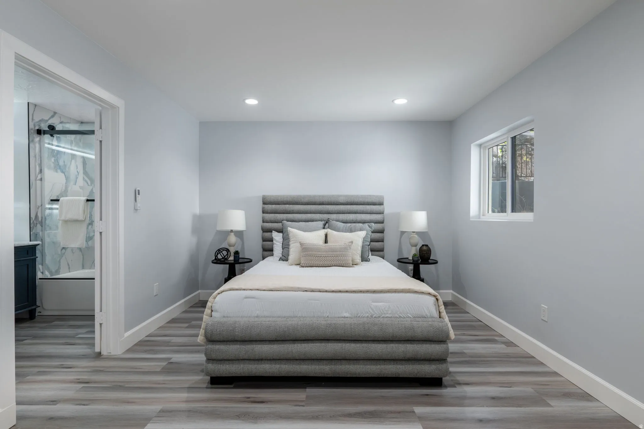 Bedroom with light wood-type flooring, recessed lighting, and connected bathroom