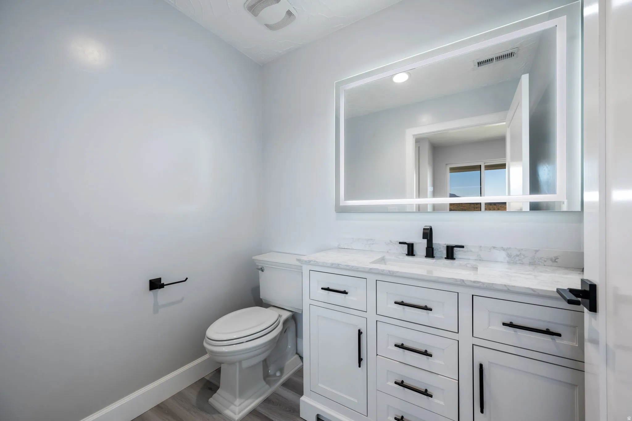 Half bathroom featuring vanity and wood finished floors
