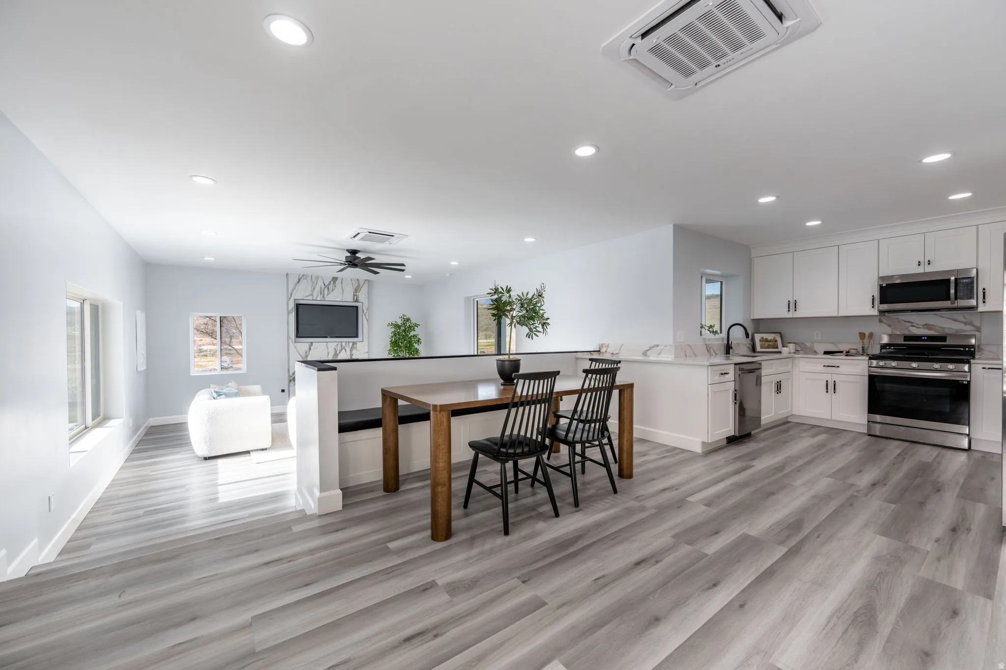 Kitchen featuring stainless steel appliances, white cabinets, a peninsula, recessed lighting, and light wood finished floors