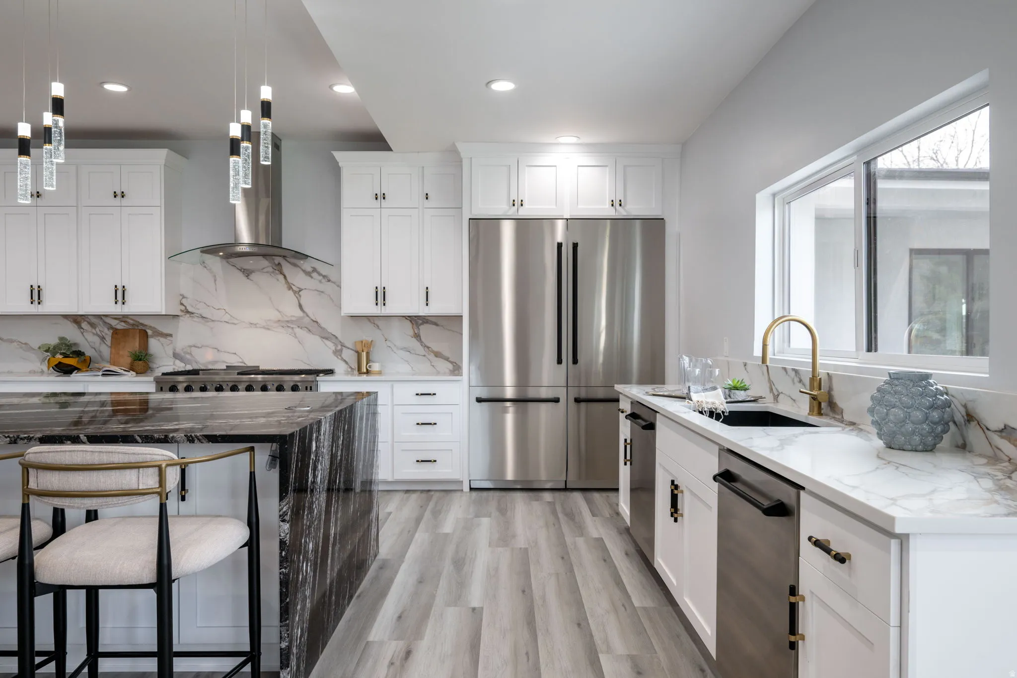 Kitchen featuring dark stone counters, stainless steel appliances, white cabinetry, and light wood finished floors