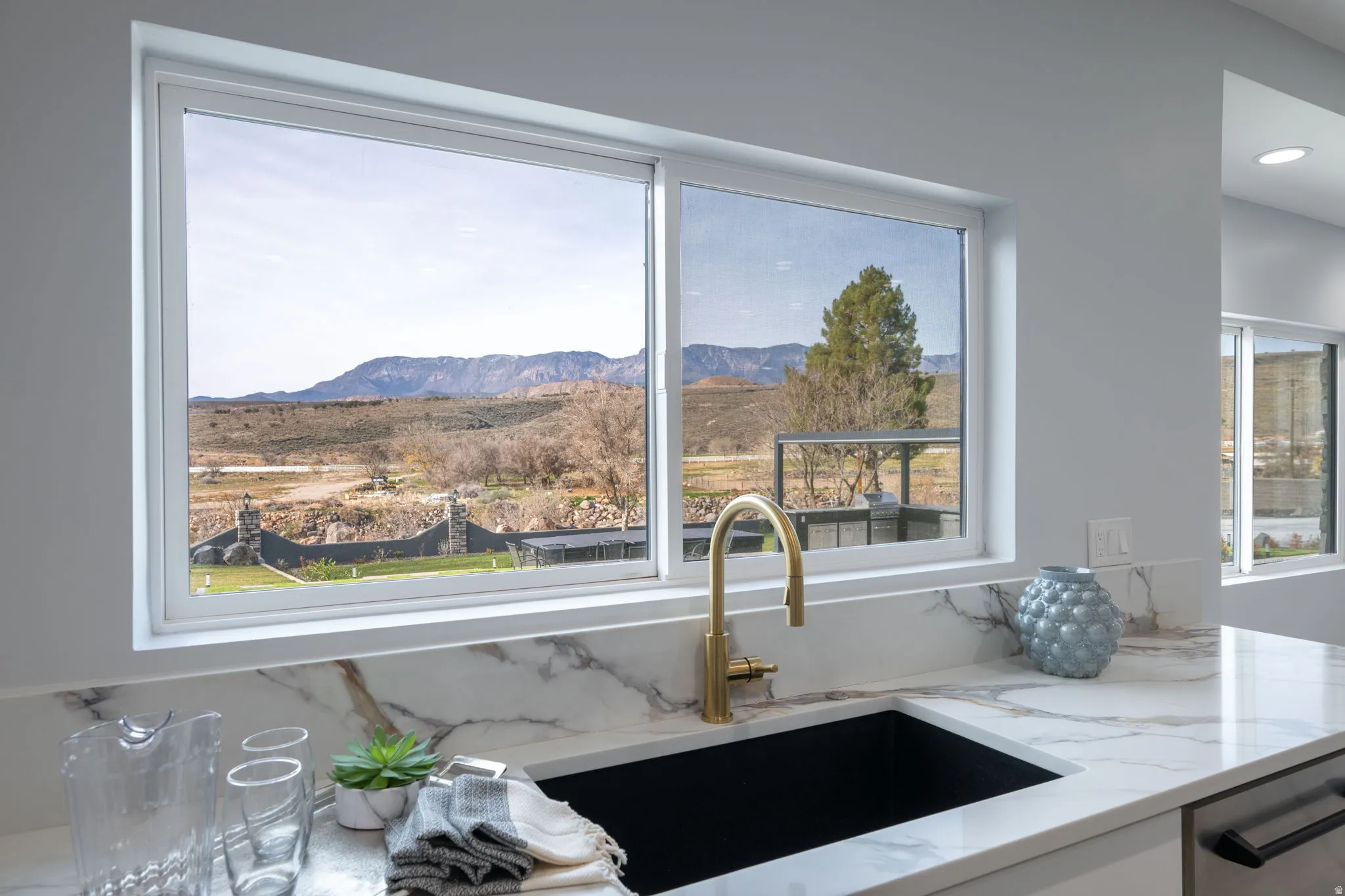 Kitchen view of light stone countertops, stainless steel dishwasher, and white cabinets