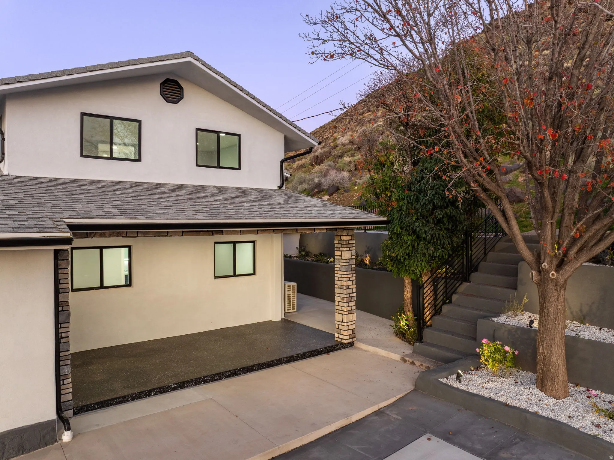 View of front of home featuring stucco siding, a patio, and a shingled roof