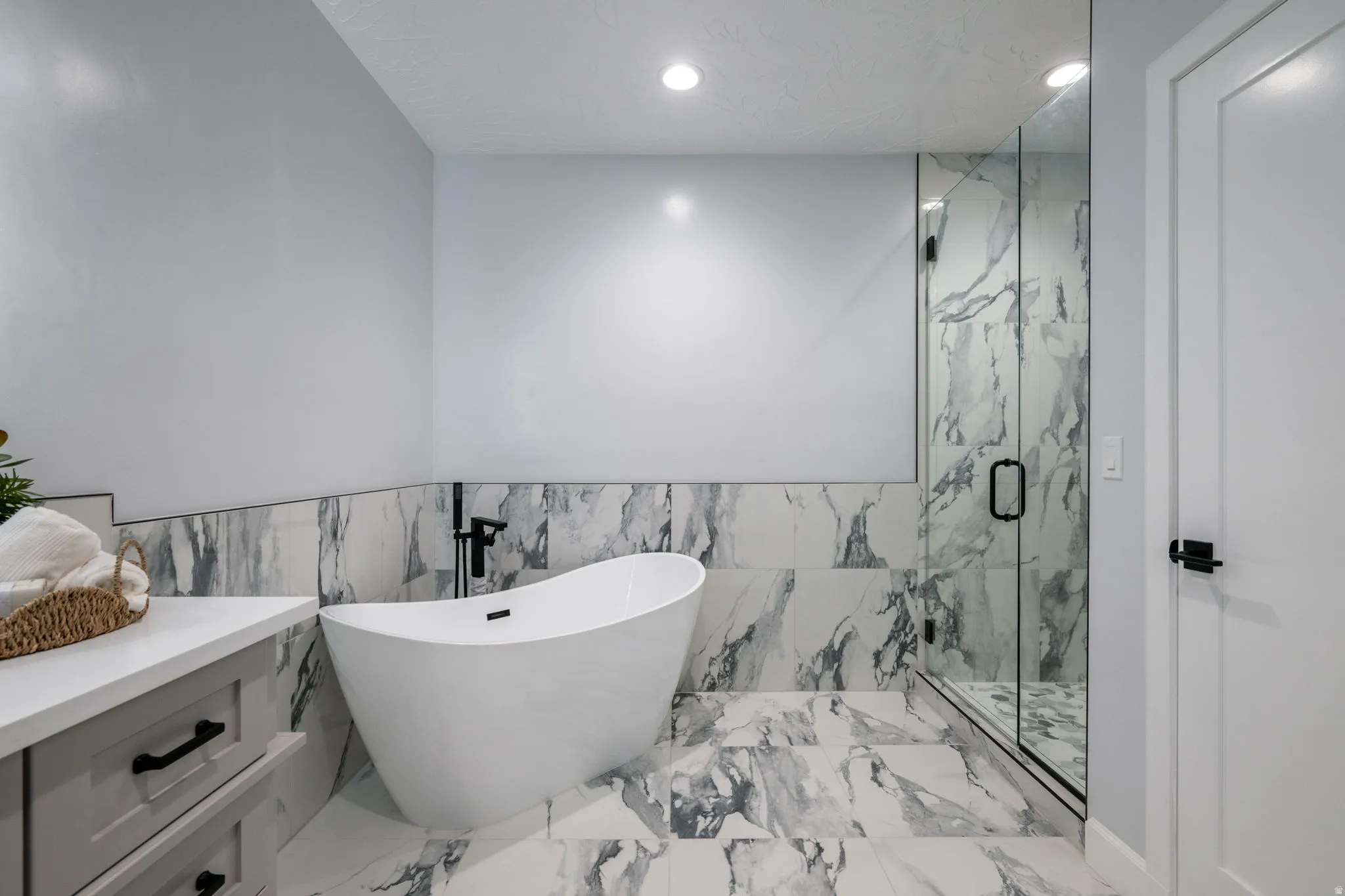 Bathroom featuring tile walls, recessed lighting, a marble finish shower, wainscoting, and a freestanding bath