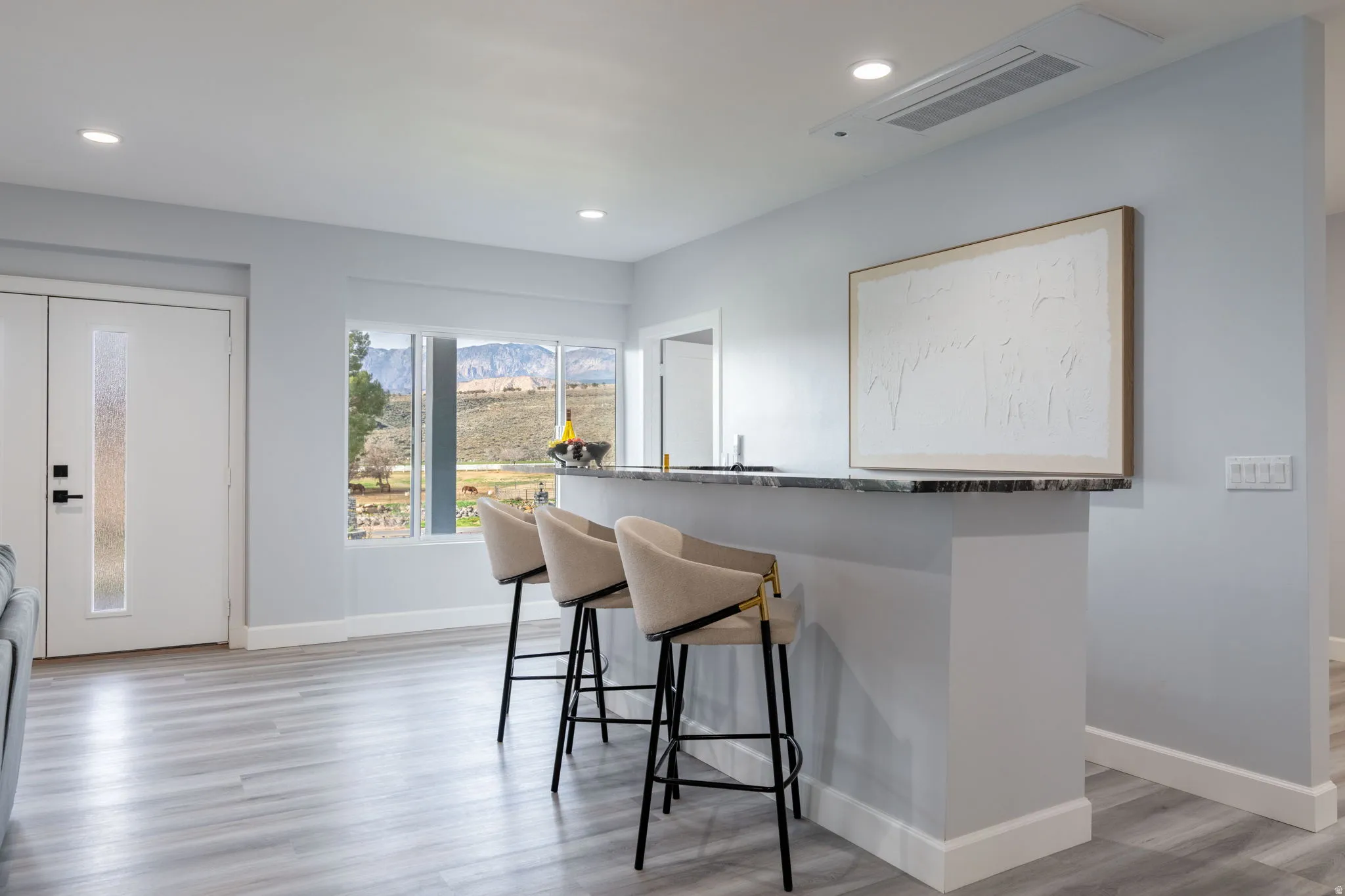 Kitchen with light wood-style floors, a kitchen bar, dark stone counters, recessed lighting, and a mountain view