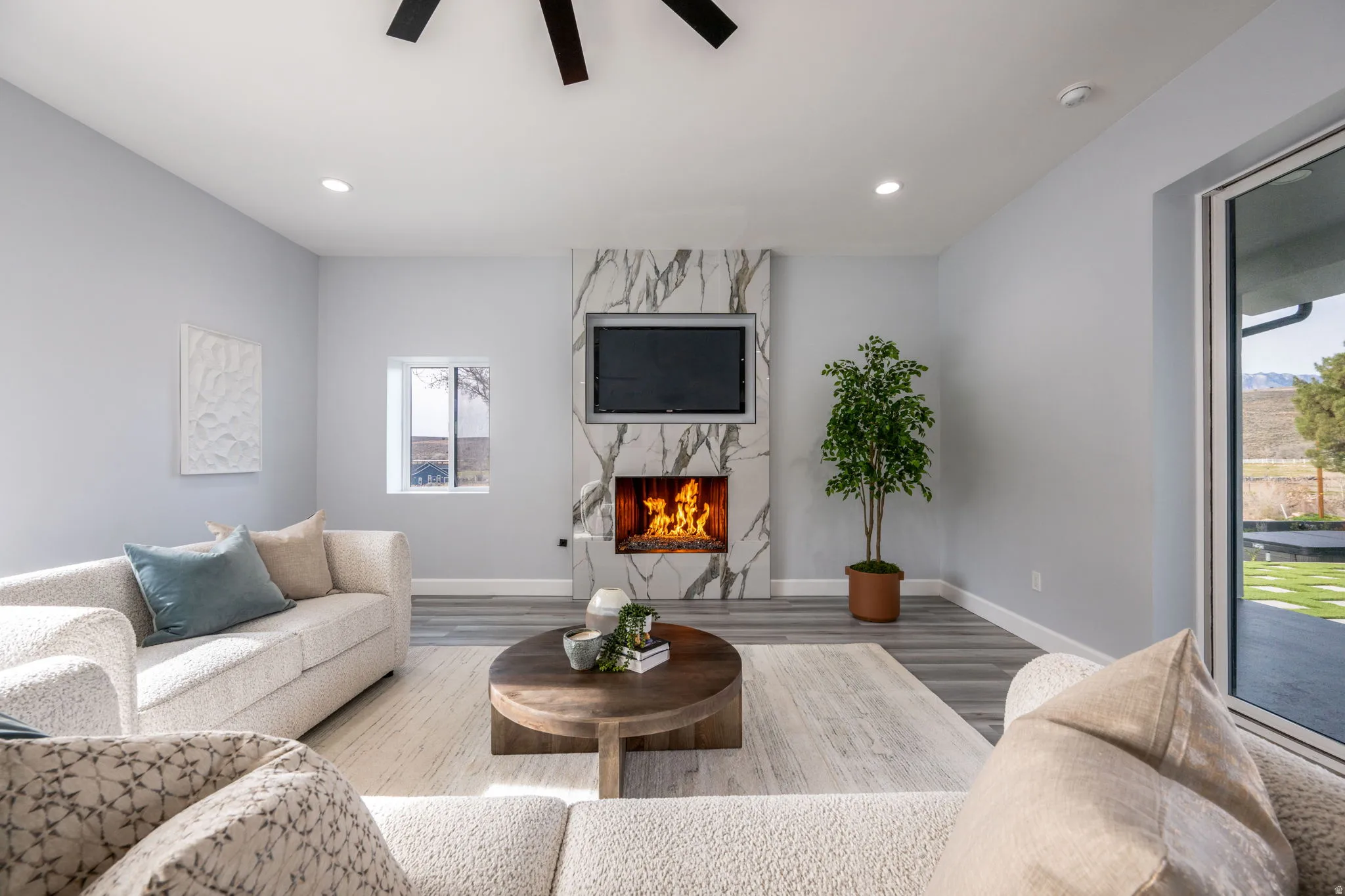 Living room with wood finished floors, a ceiling fan, and a fireplace