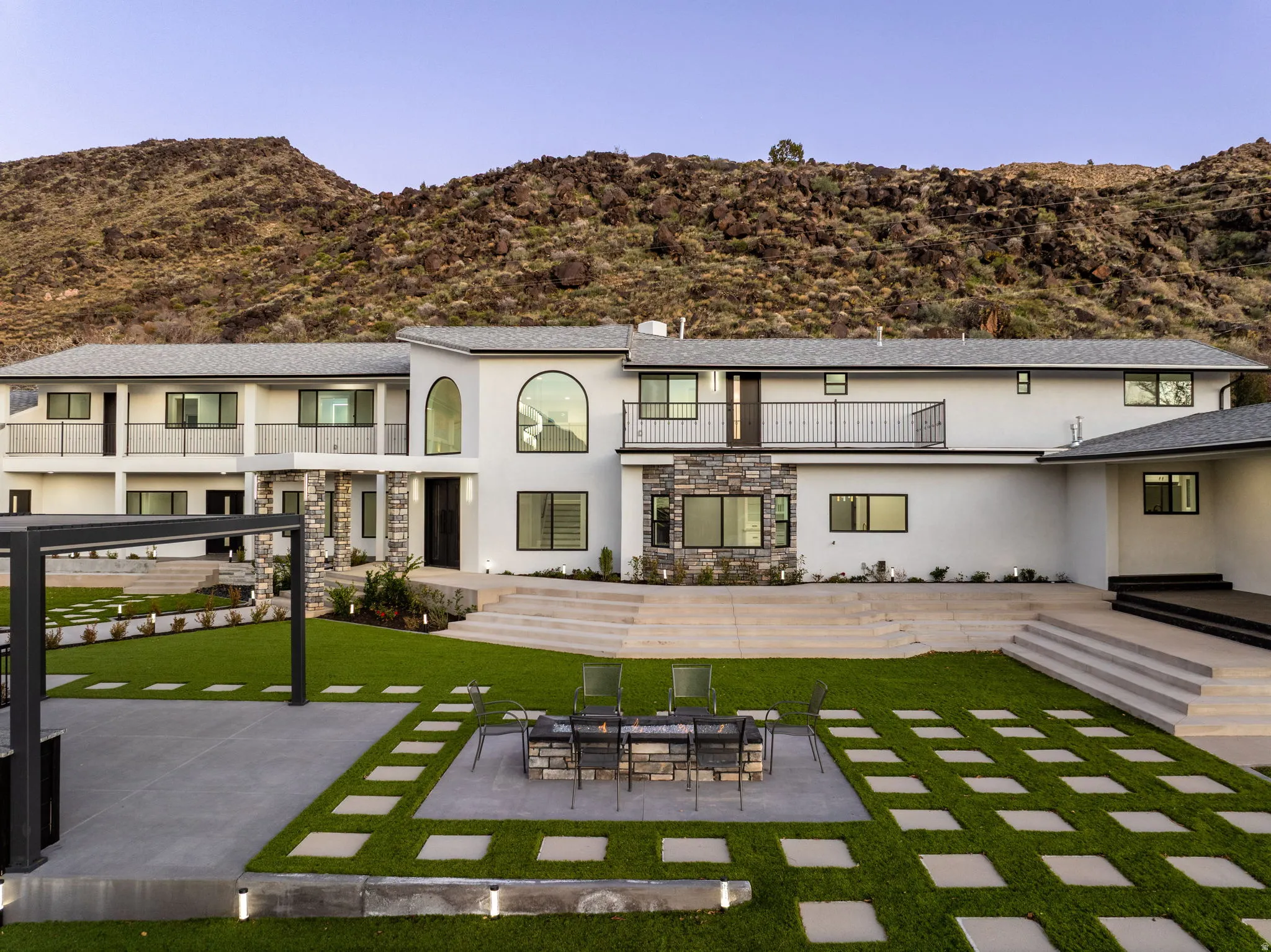 Rear view of house featuring a patio, stone siding, and stucco siding