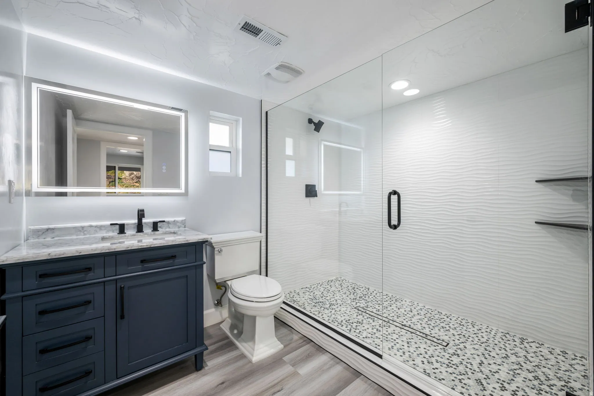 Bathroom featuring vanity, a shower stall, light wood finished floors, and recessed lighting