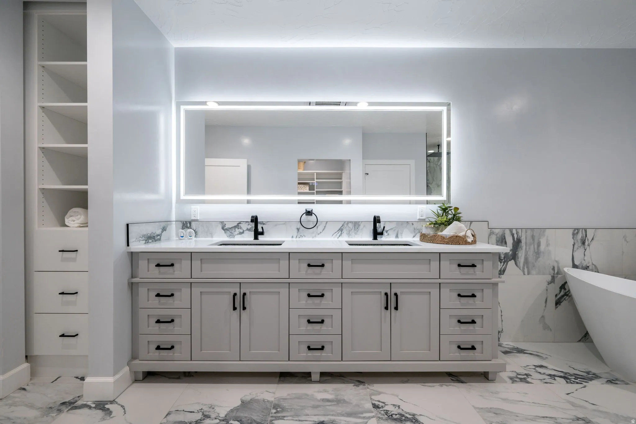 Bathroom featuring a freestanding bath, double vanity, and wainscoting