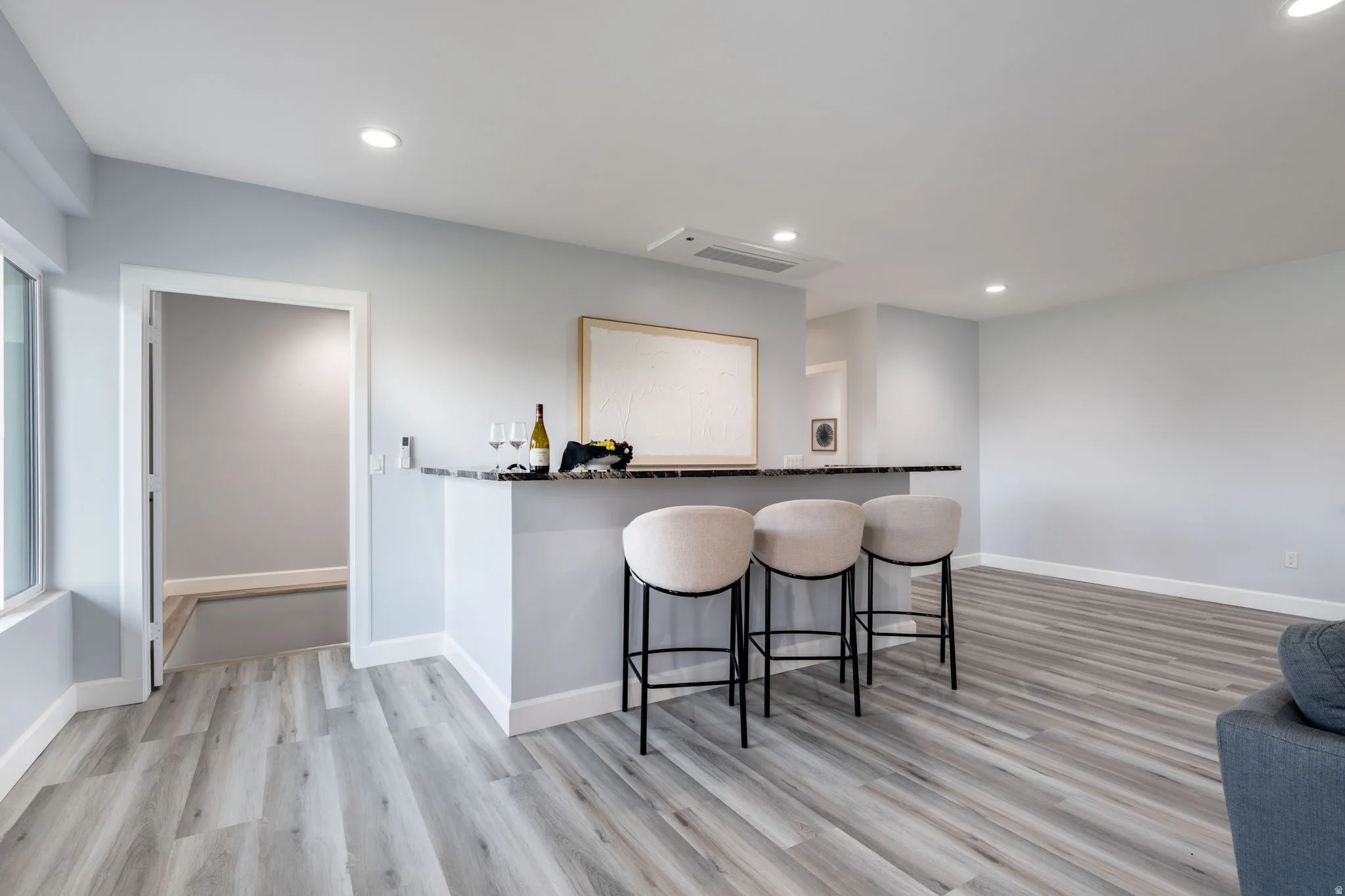 Bar area featuring light wood-type flooring and recessed lighting