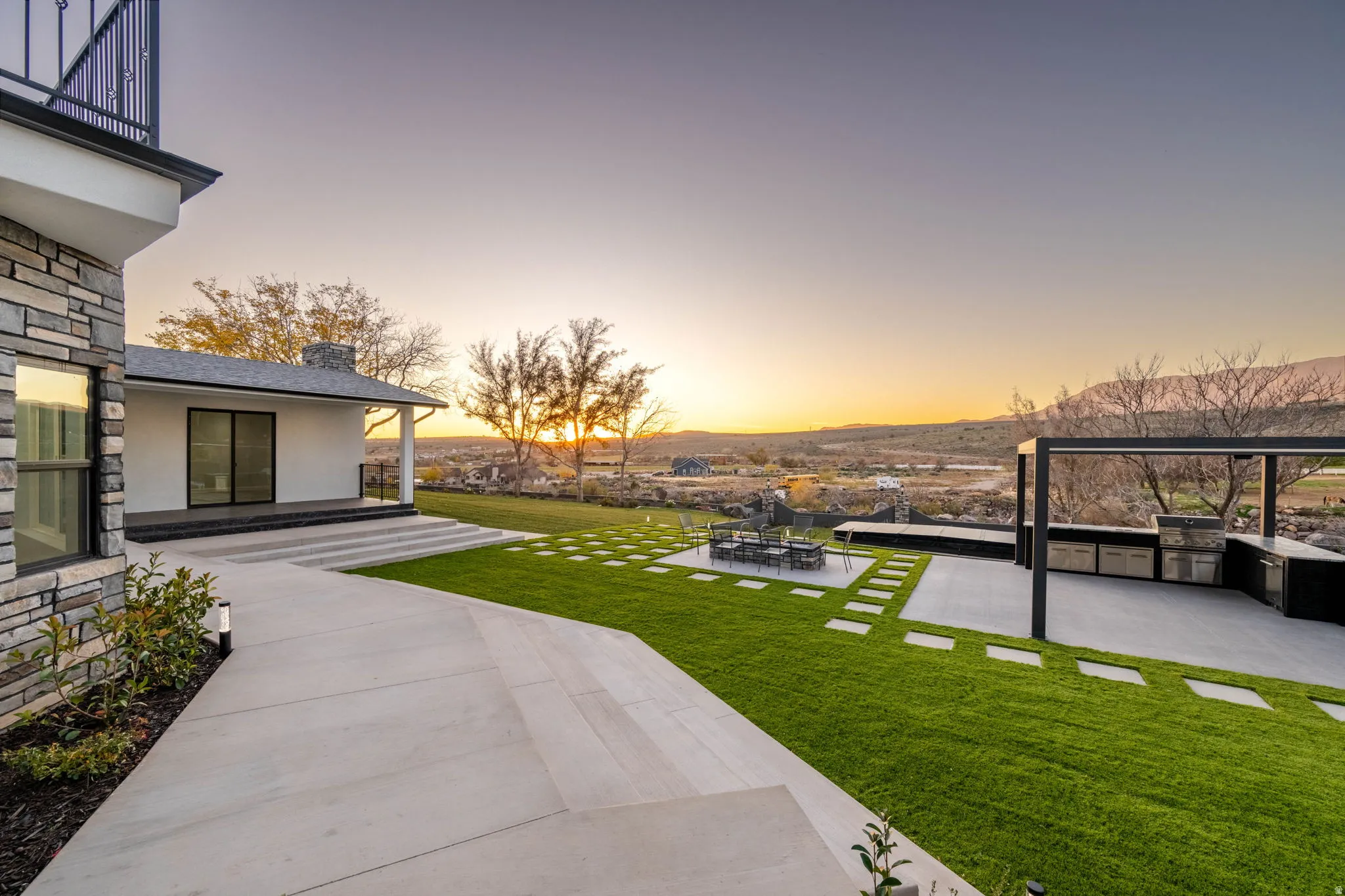 View of grassy yard with an outdoor kitchen and a patio