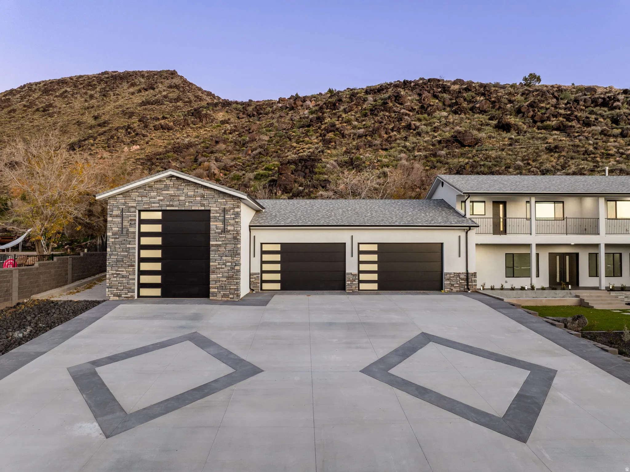 View of front facade with stone siding, concrete driveway, stucco siding, a garage, and a mountain view