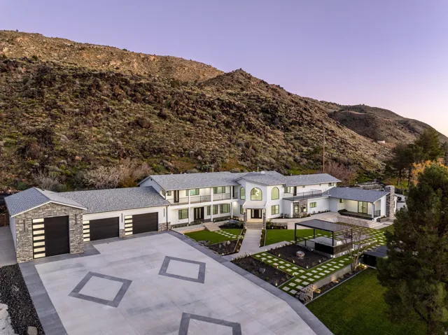 View of front facade with a mountain view, stone siding, concrete driveway, an attached garage, and a patio