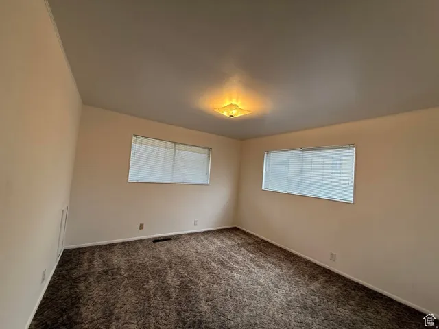 Spare room with healthy amount of natural light and dark colored carpet