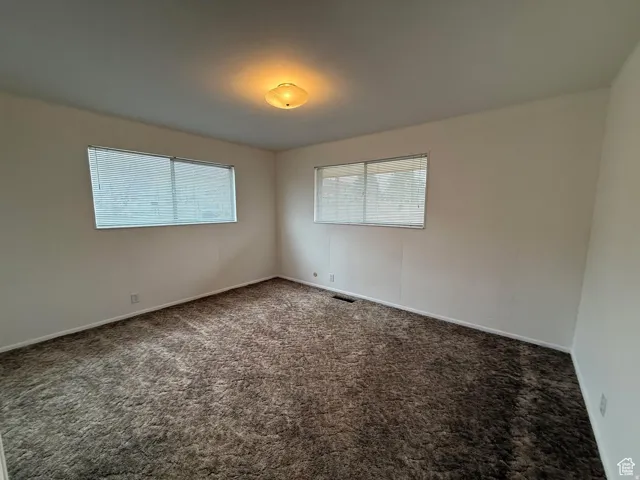 Unfurnished room with dark colored carpet and baseboards