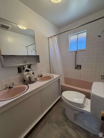 Full bathroom with double vanity, shower / tub combo, and tasteful backsplash