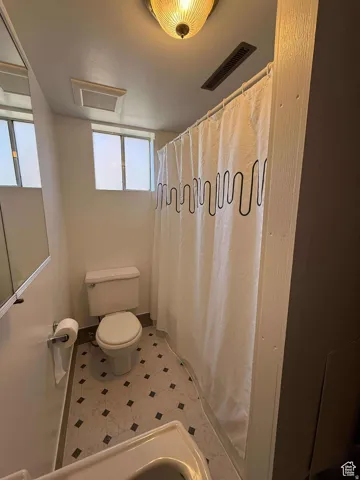 Bathroom with curtained shower and light tile patterned floors