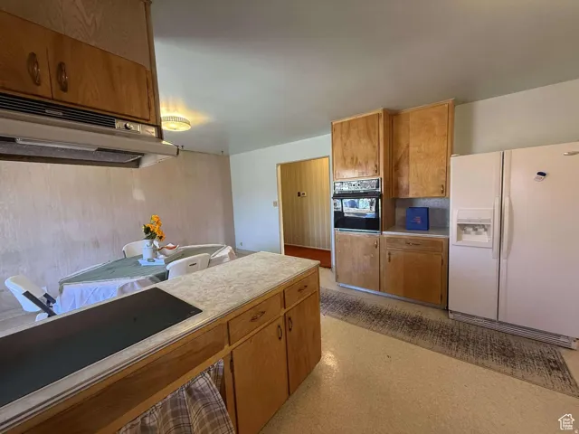 Kitchen with black appliances, wood finish cabinetry, and light countertops
