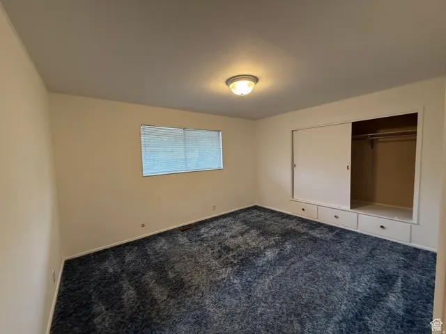 Unfurnished bedroom with dark colored carpet and a closet