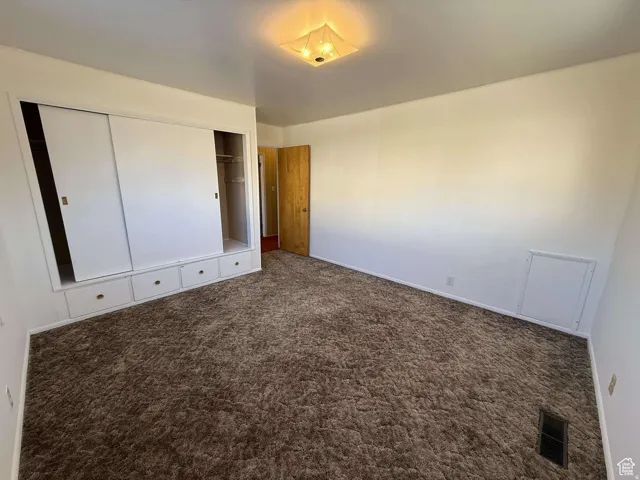 Unfurnished bedroom with a closet and dark carpet