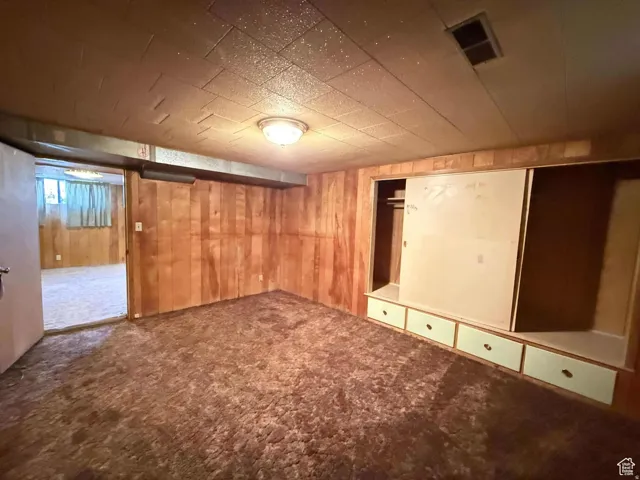 Finished basement featuring dark carpet and wood walls