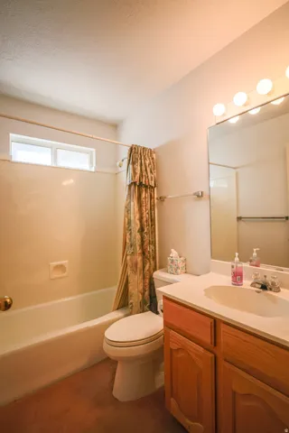 Full bath with vanity, shower / bathtub combination with curtain, and dark carpet