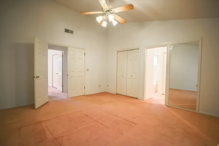 Unfurnished bedroom featuring light colored carpet, a closet, vaulted ceiling, and ceiling fan