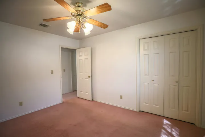 Unfurnished bedroom featuring carpet, a ceiling fan, and a closet