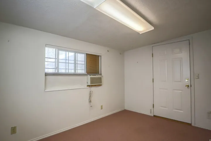 Carpeted spare room with a textured ceiling and cooling unit