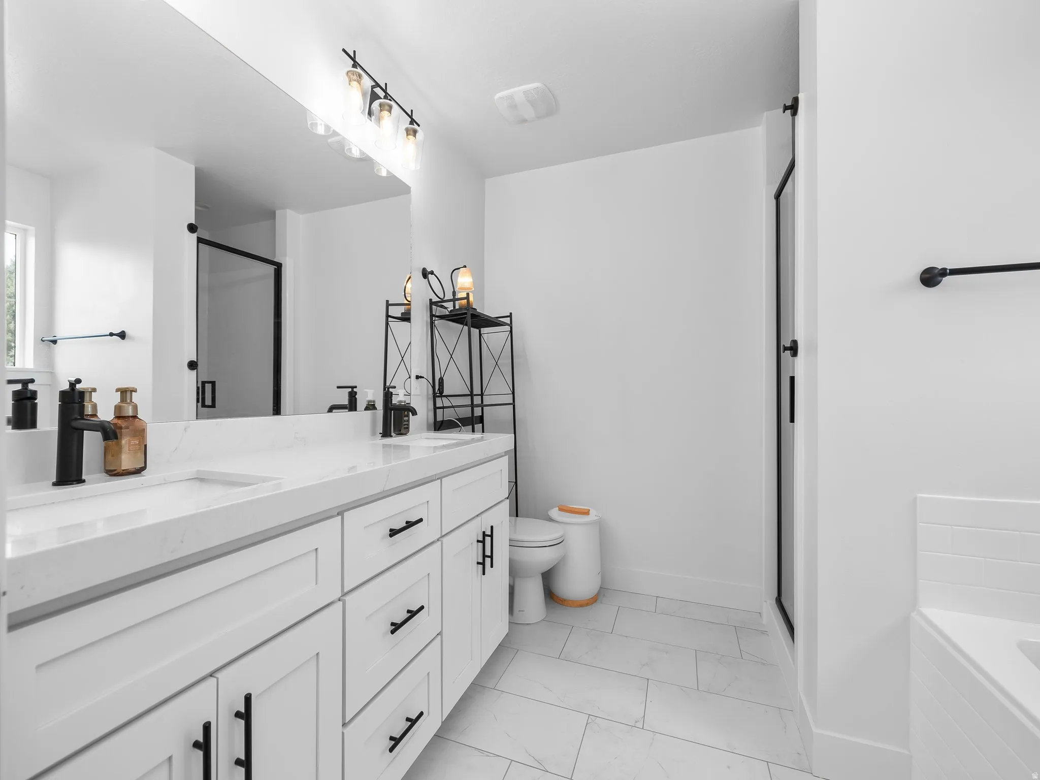 Full bathroom featuring a shower stall, double vanity, a bath, and light marble finish floors