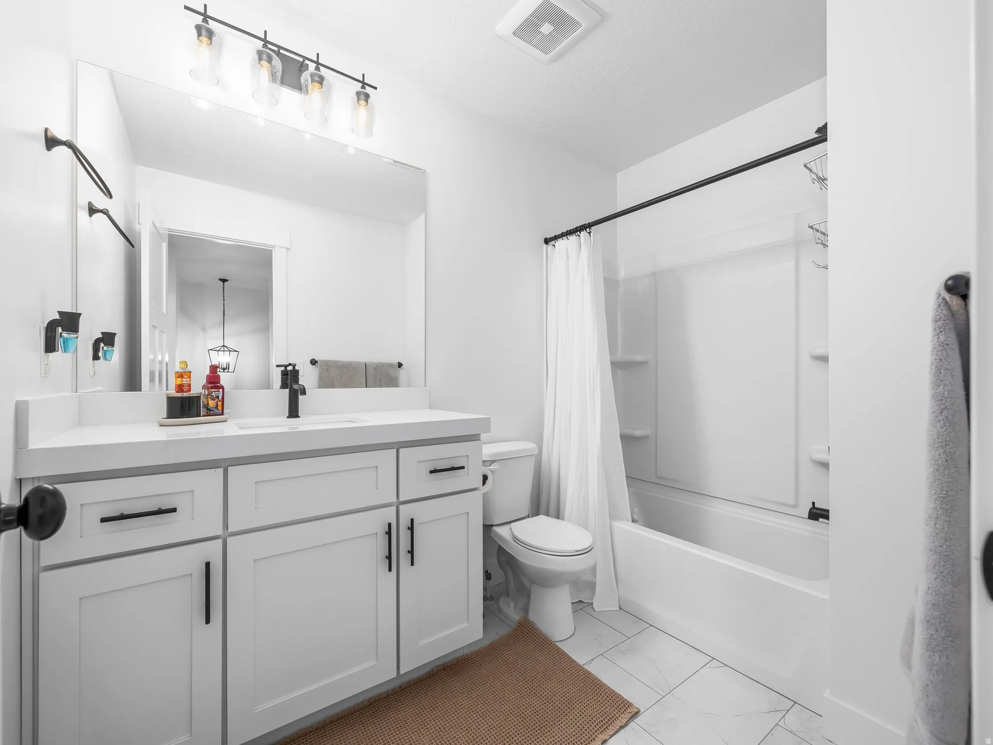 Full bathroom featuring vanity, shower / bathtub combination with curtain, and light marble finish floors