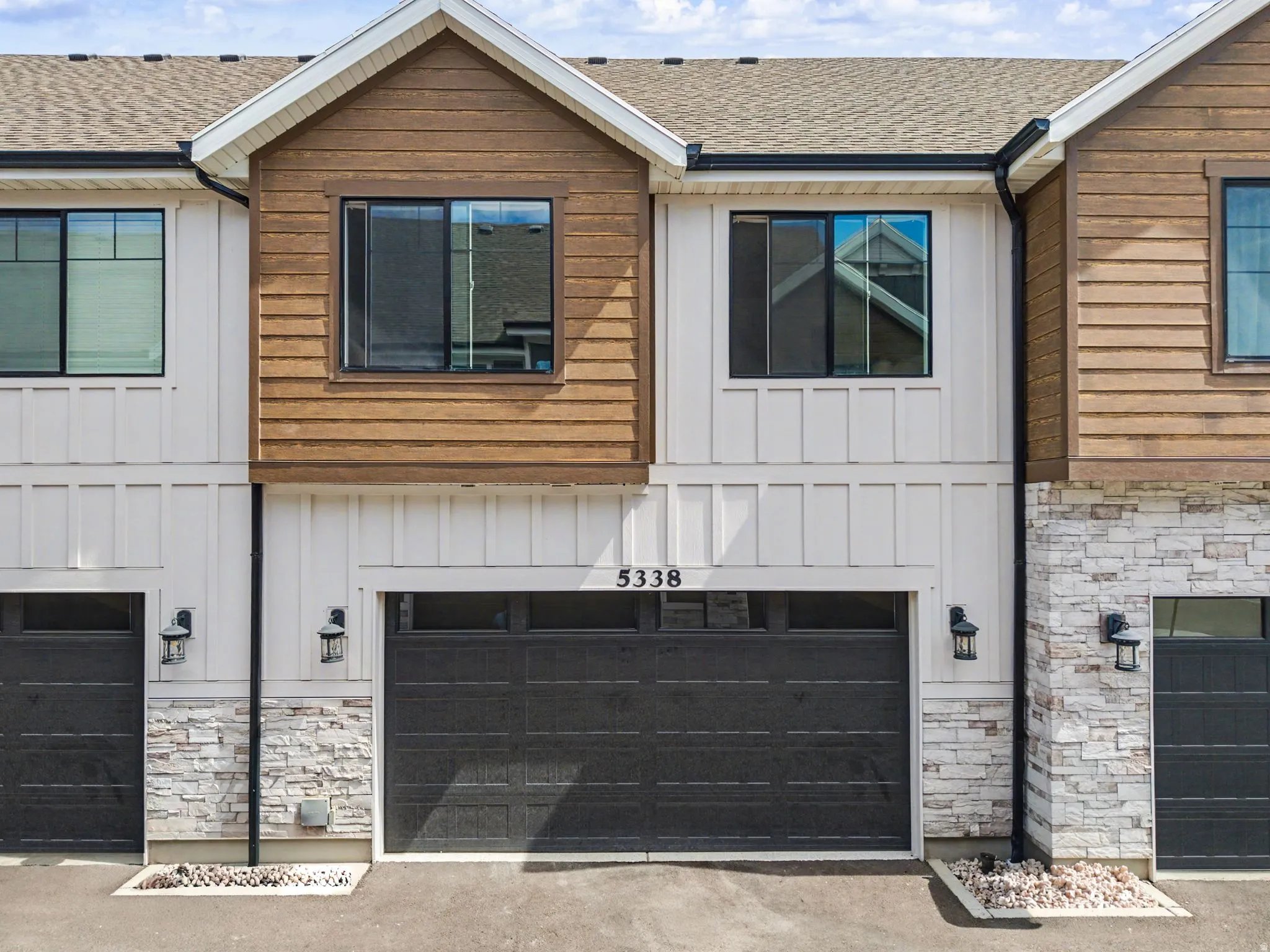 View of front of home featuring board and batten siding, stone siding, a shingled roof, and a garage