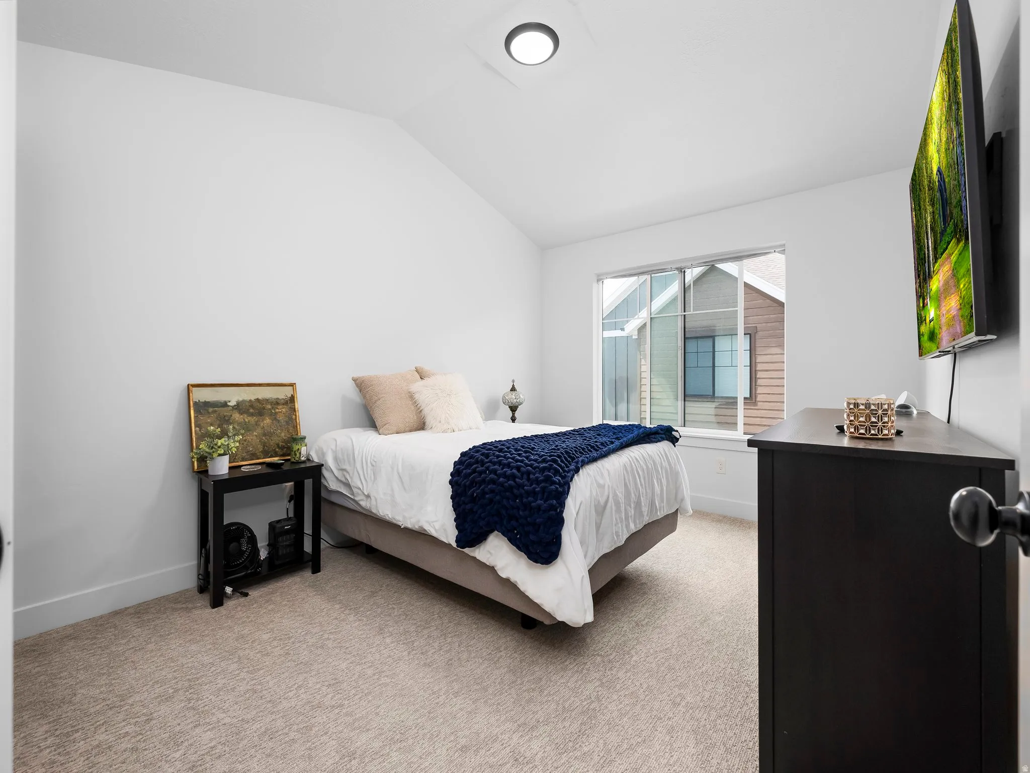 Bedroom featuring lofted ceiling and light carpet