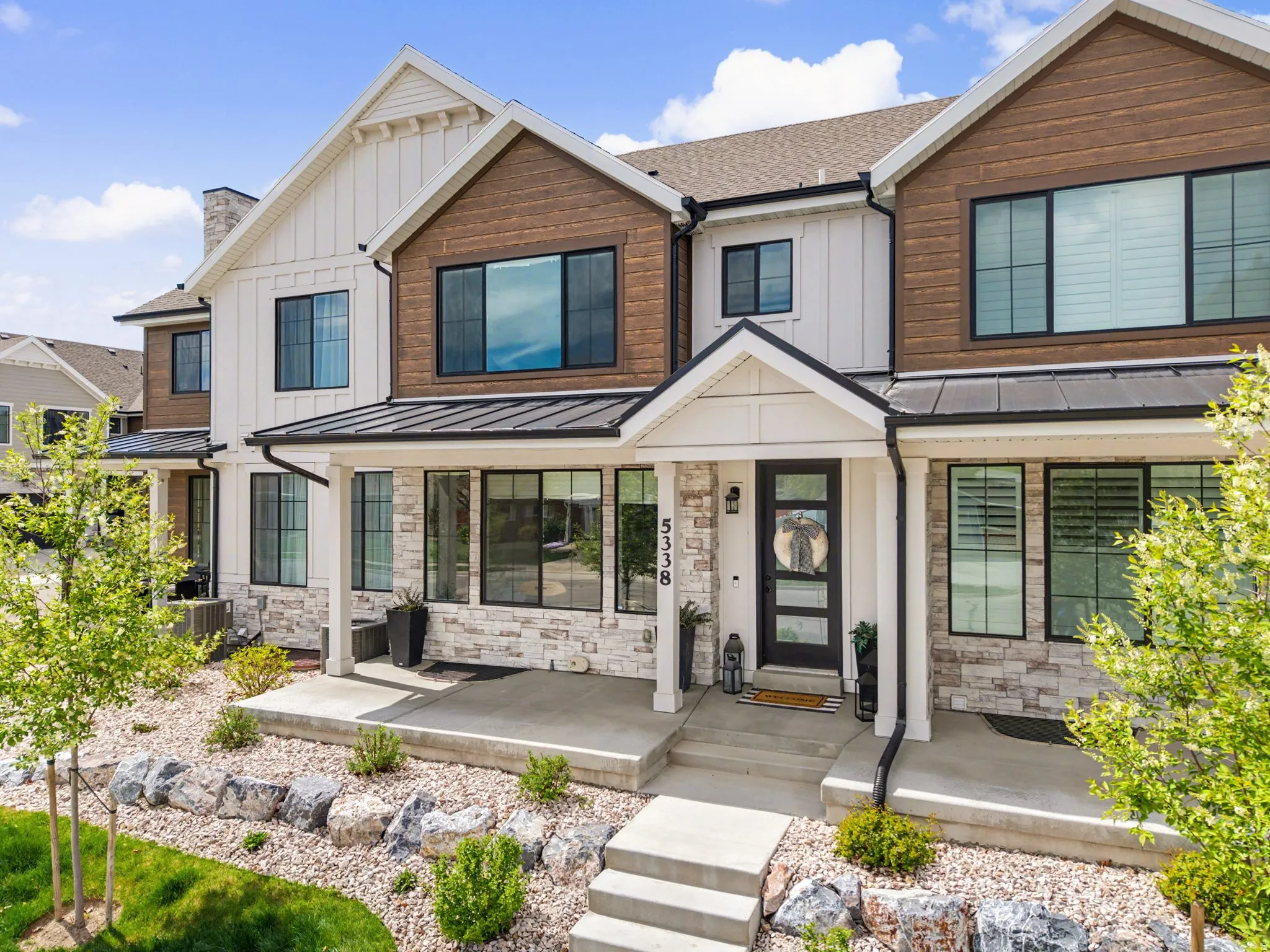 View of front of house featuring a standing seam roof, board and batten siding, stone siding, and a porch
