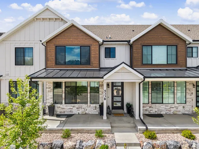 View of front of house featuring stone siding, a standing seam roof, a porch, board and batten siding, and roof with shingles