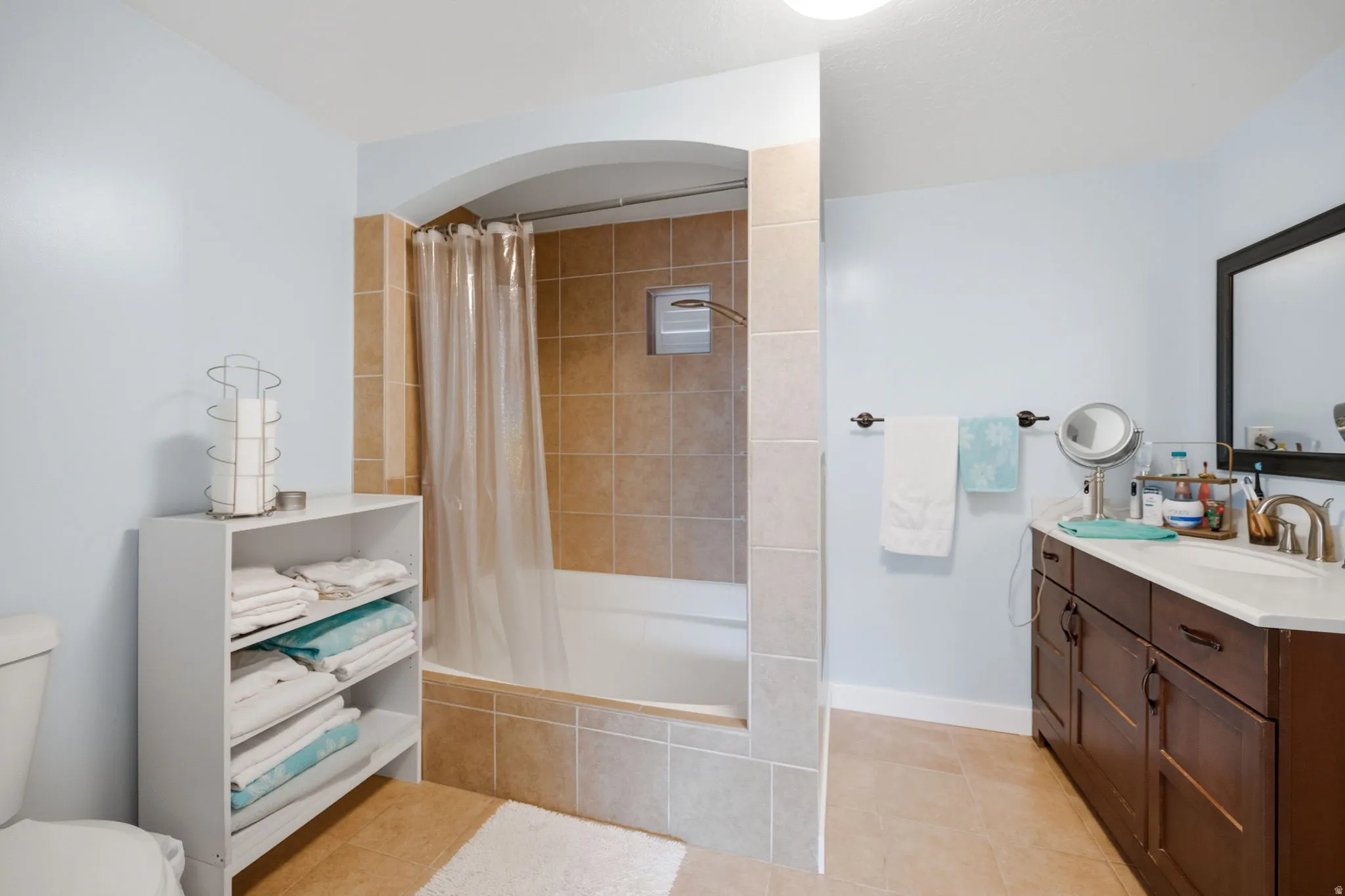 Bathroom with vanity, tiled shower / bath, and light tile patterned floors