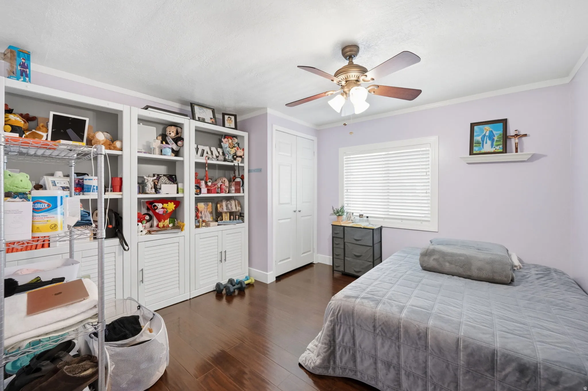 Bedroom featuring dark wood-style floors, a ceiling fan, ornamental molding, and a closet