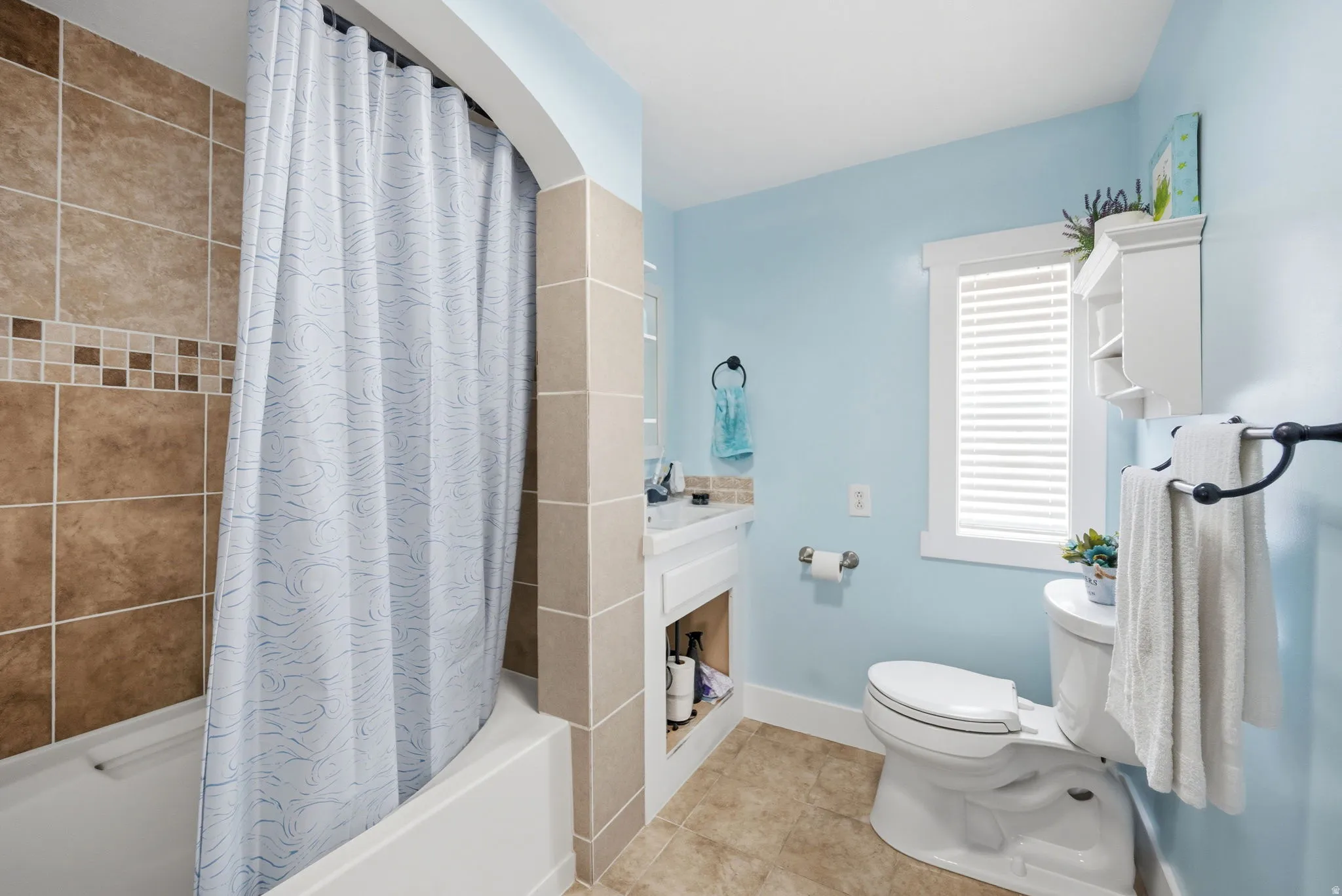 Bathroom featuring light tile patterned floors and shower / bath combo with shower curtain