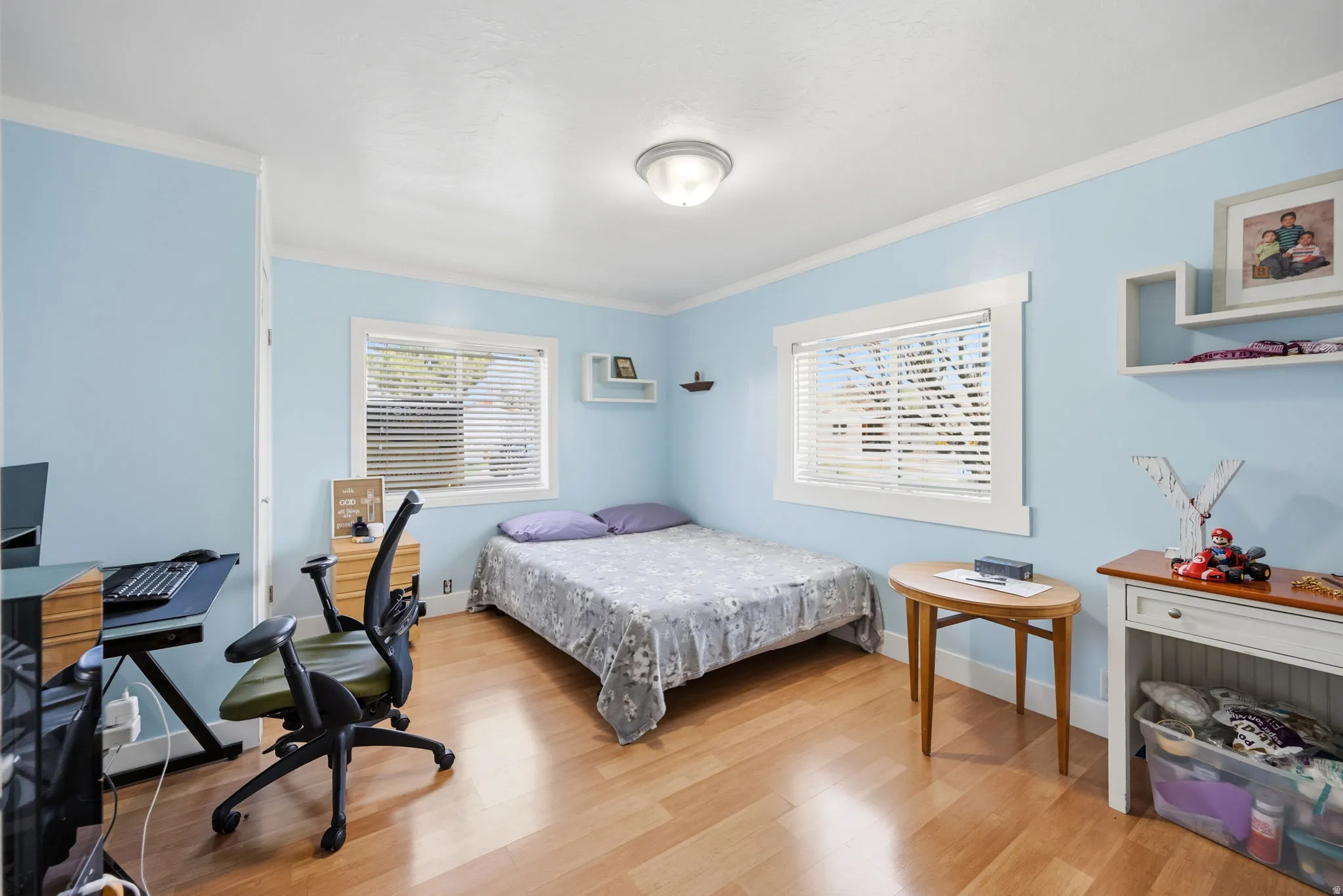 Bedroom with an office area, light wood finished floors, and ornamental molding
