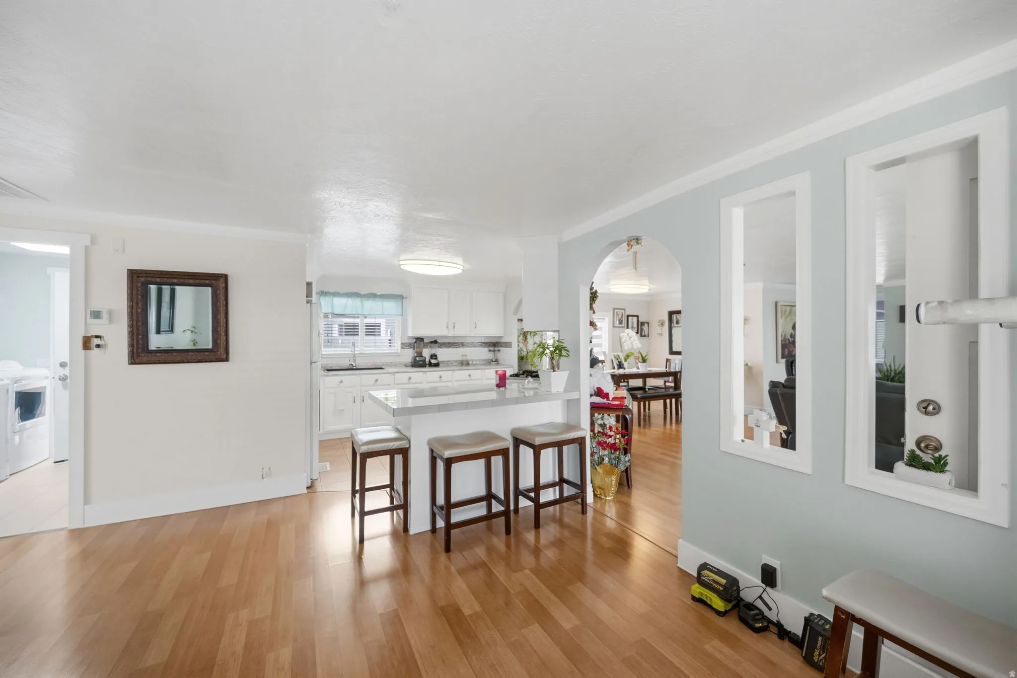 Kitchen featuring white cabinetry, a breakfast bar area, arched walkways, a peninsula, and ornamental molding
