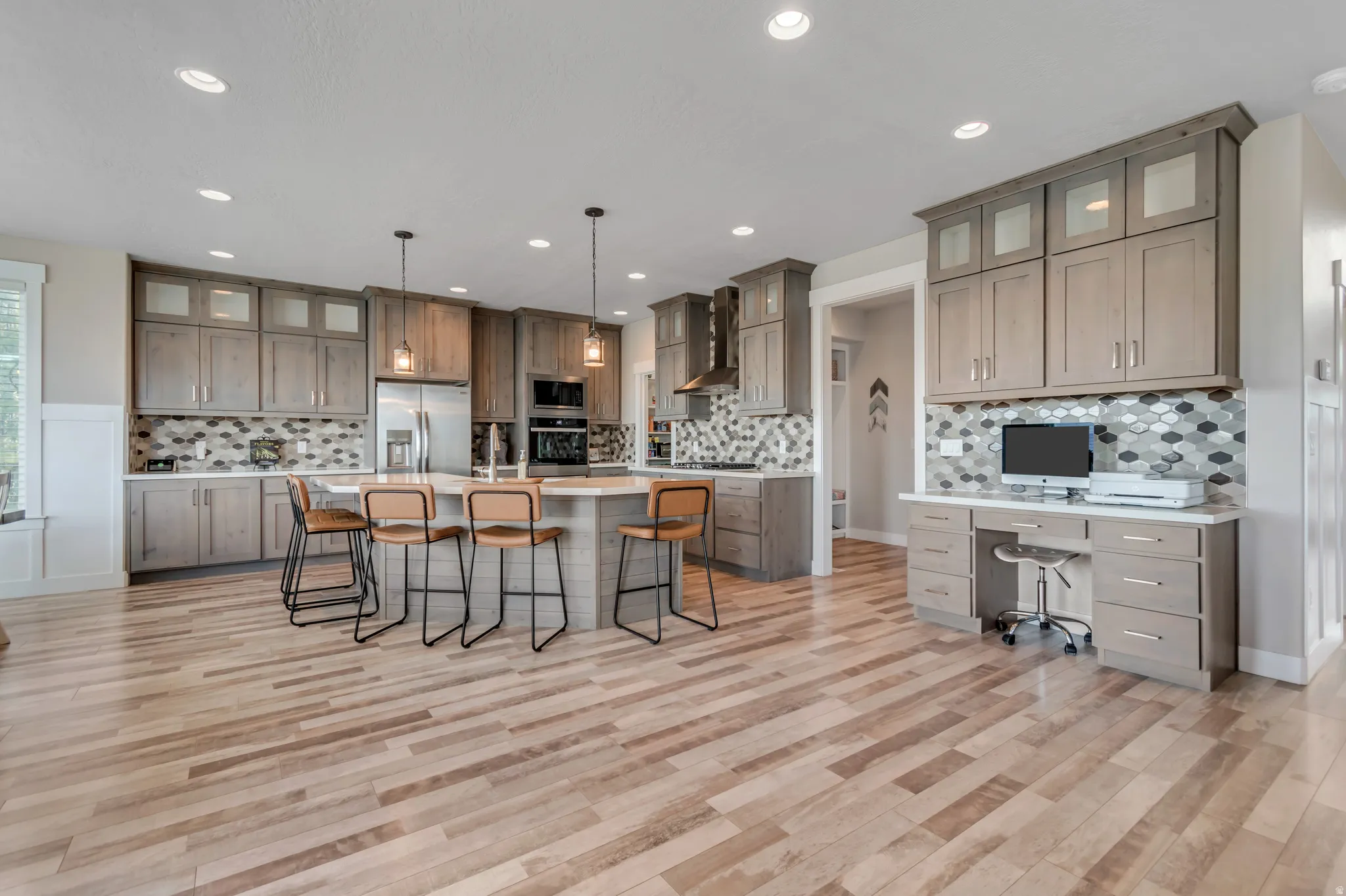Kitchen featuring a breakfast bar area, glass insert cabinets, hanging light fixtures, and a kitchen island with sink